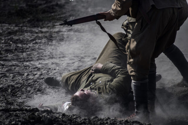 Leżący polski żołnierz, a nad nim pochylony żołnierz Armii Czerwonej z karabinem w ręku.