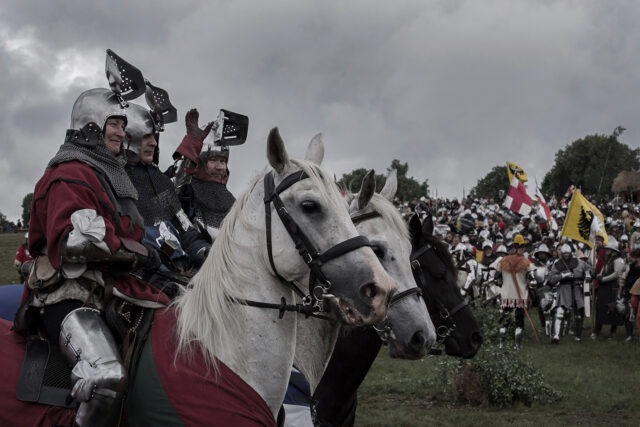 Rycerze na koniach witają się z tłumem.